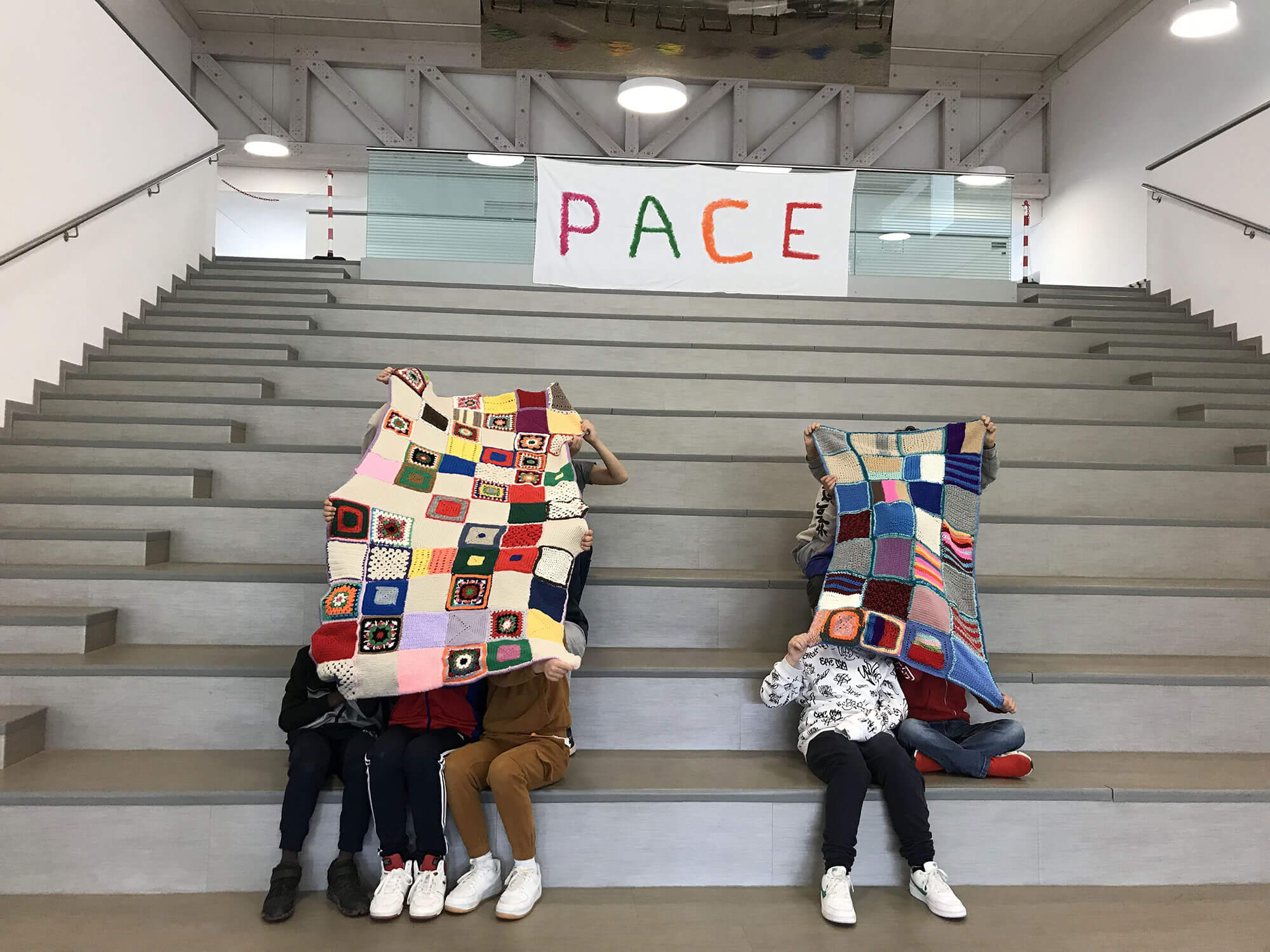 Bambini_con_coperta_su_scale_e_bandiera_della_pace